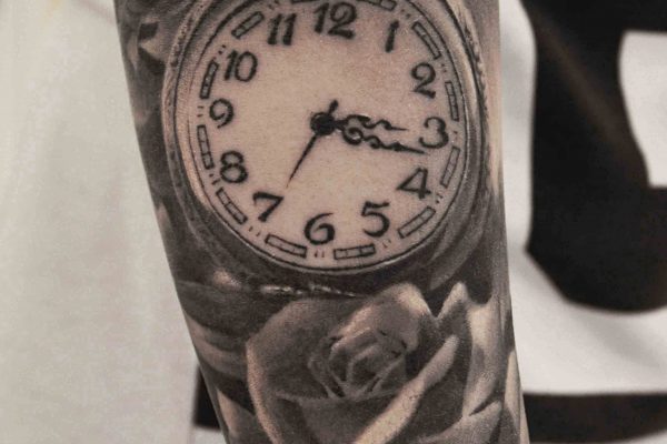 Tattoo von einer Uhr und einer Rose auf dem Arm